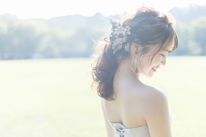 花の髪飾りを付けてドレスを着て笑っている女性の横顔